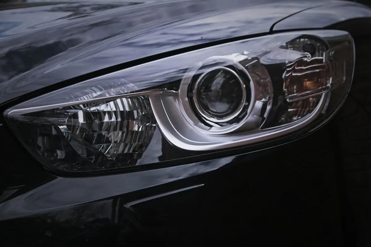 Close-up of a clear projector headlight on a dark grey car
